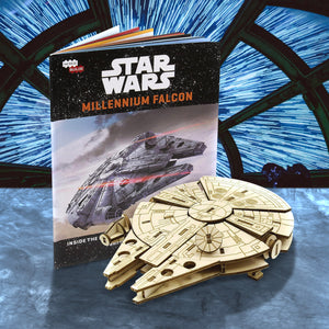 A wooden model of the spaceship Millennium Falcon from the Star Ward movies, sitting on a marble table. Next to the model is an assembly guide book. In the background is the Millennium Falcon's cockpit window, with white streaks representing the jump to light speed.