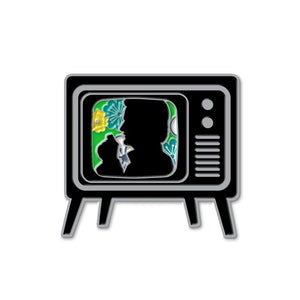 A brass pin in the shape of an old TV set, on a white background. On the screen is a black silhouette of the Trickster character from Supernatural, surrounded by green and yellow flowers.